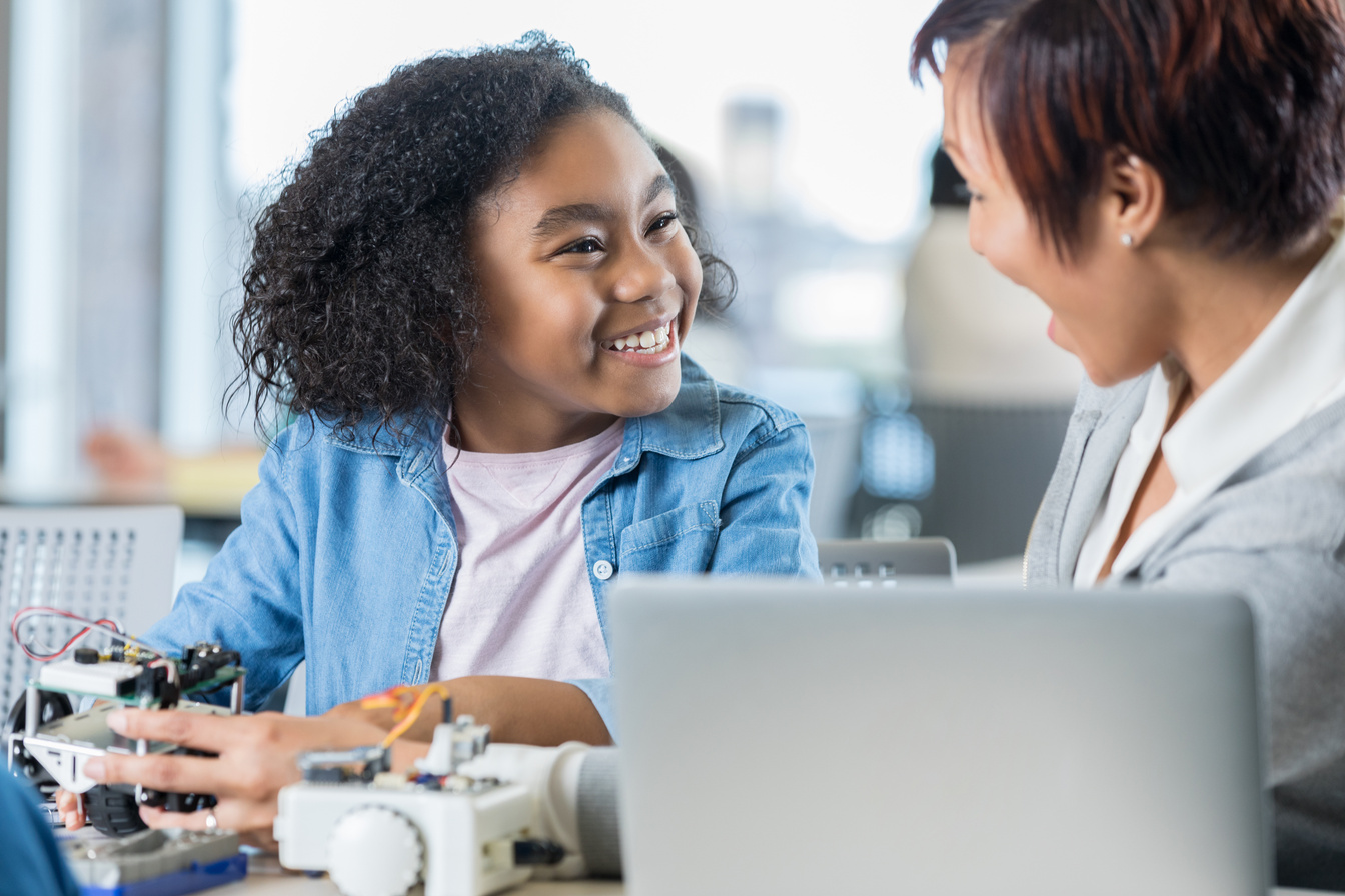 Cheerful teacher helps student in tech class